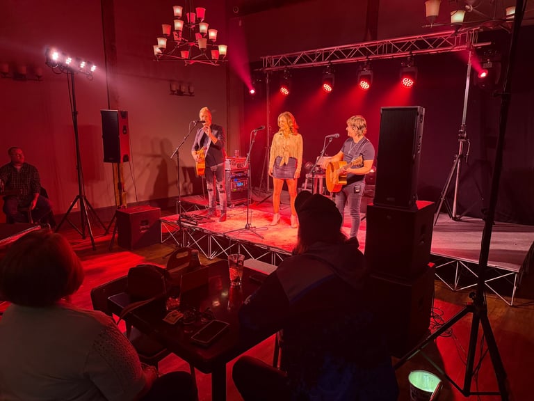 Live band performing on stage with red lighting, musicians playing instruments under professional stage setup